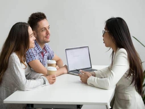 smiling millennial couple listening INSURANCE AGENT consulting customers Insurance advisor explaining coverage options to Austin clients.